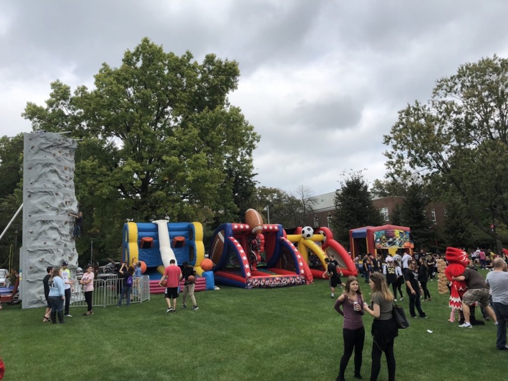 outdoor campus event with rock climbing wall, bounce houses