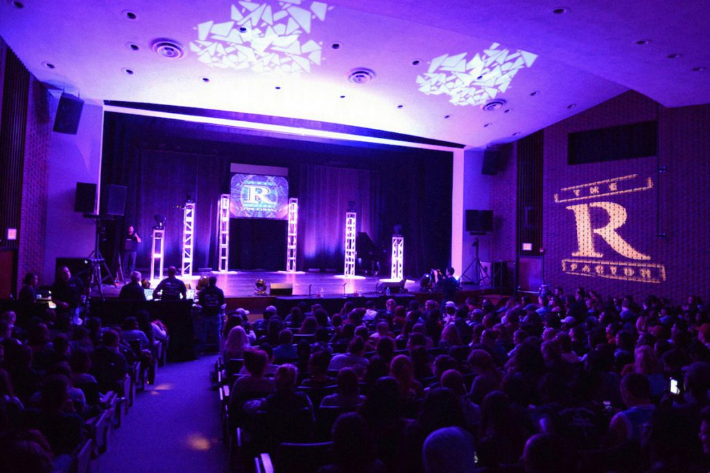 college event set up in auditorium with purple lighting and custom school monogram gobos