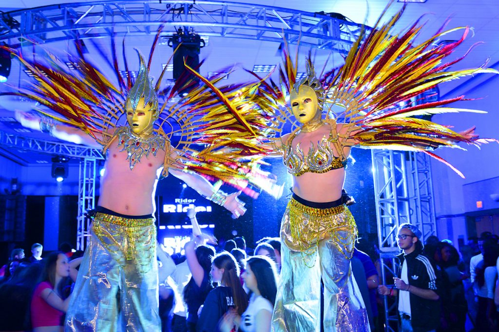 live performing stilt walkers, dressed in gold at a campus event
