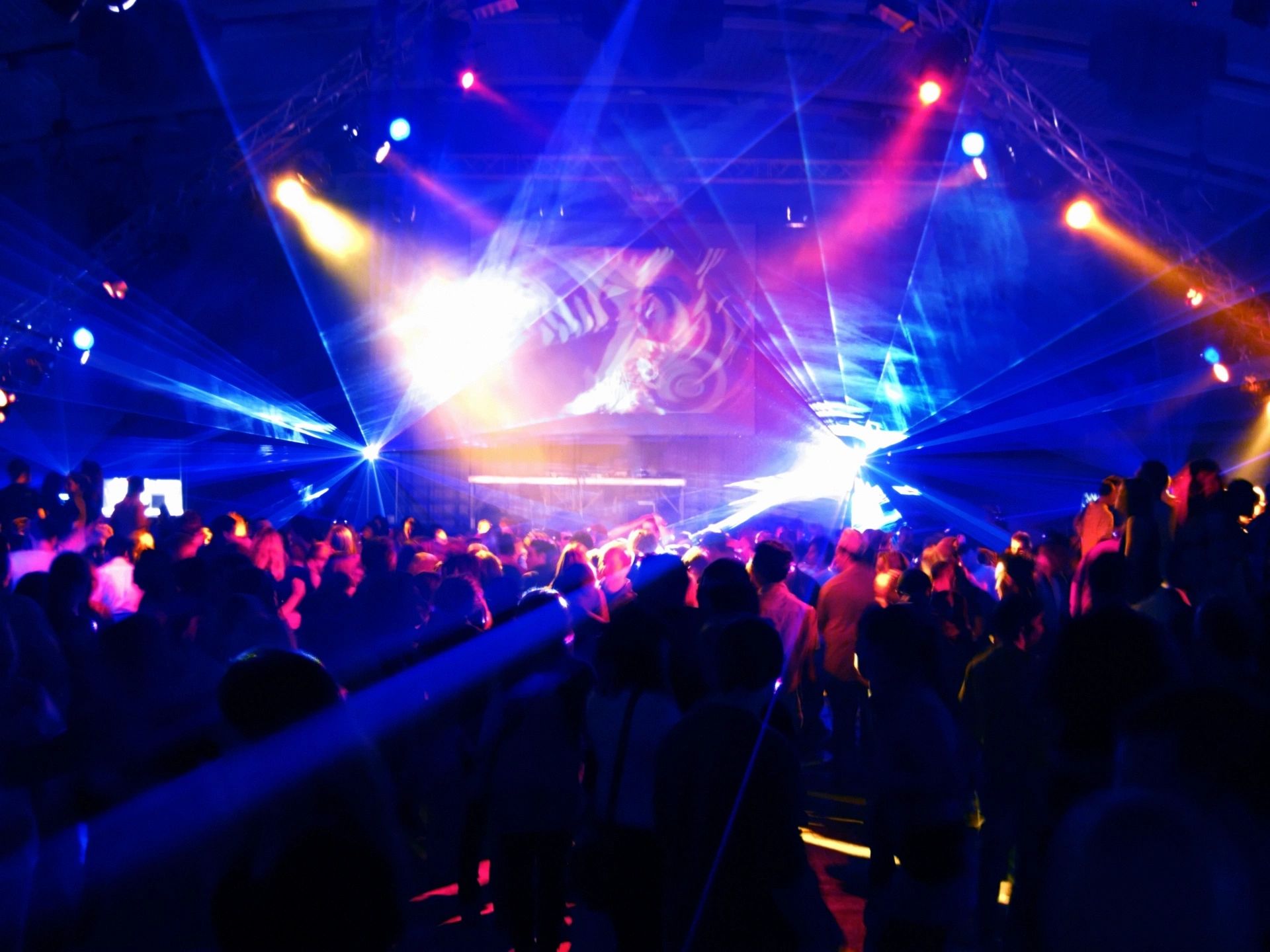 dance floor with dramatic, colorful spotlights and silhouettes of people dancing