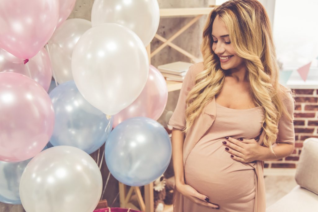 woman looking at pink and blue balloons at baby shower