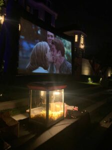 Backyard outdoor movie screen rental at night with popcorn machine